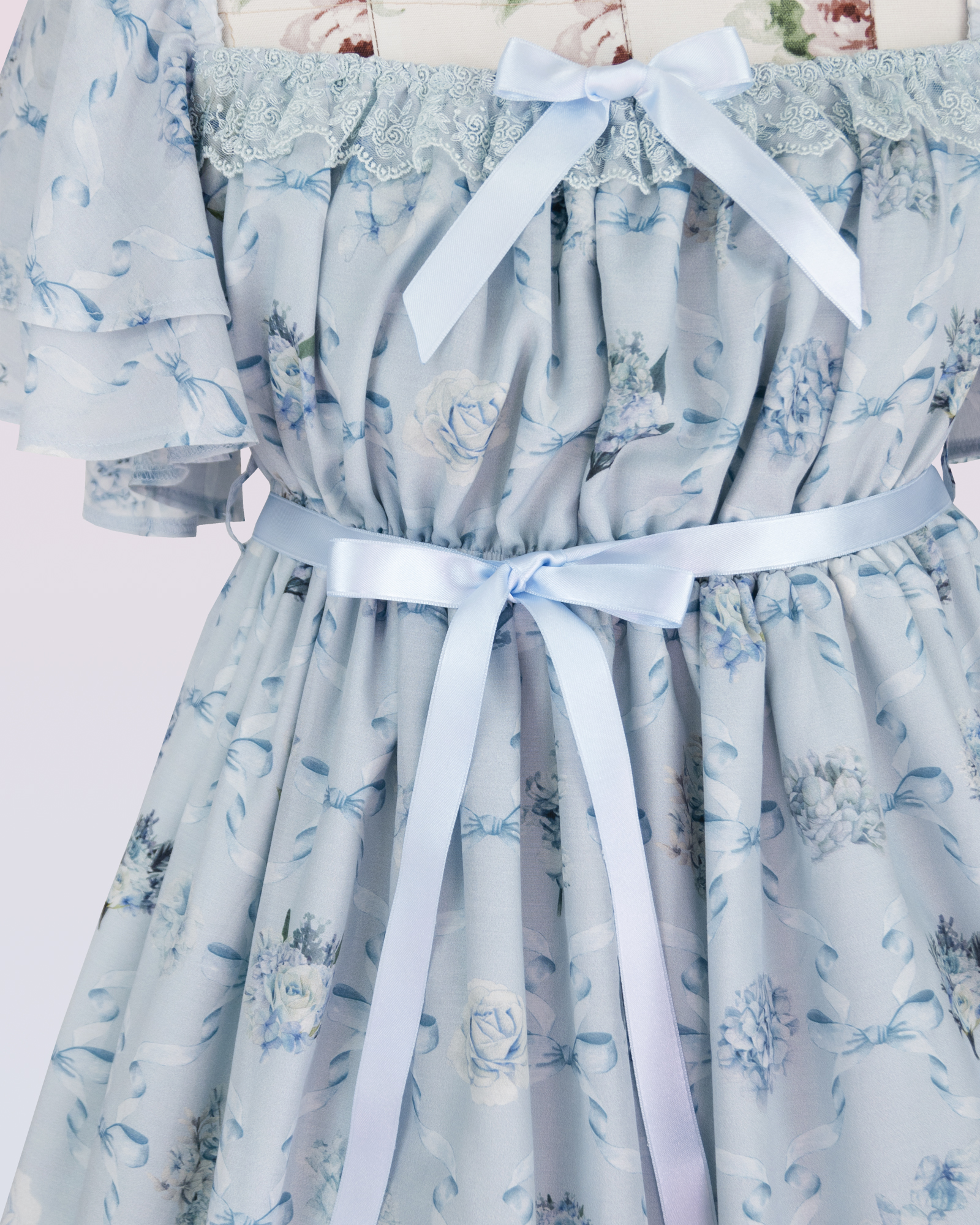 短い袖および花およびリボンの印刷物が付いている軽い青いシフォンの服