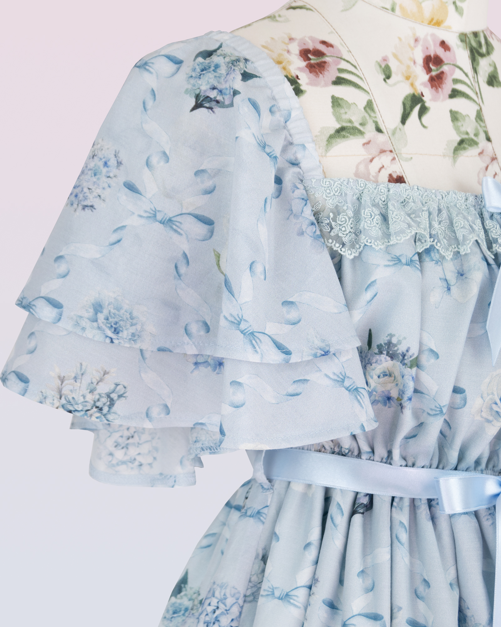 短い袖および花およびリボンの印刷物が付いている軽い青いシフォンの服