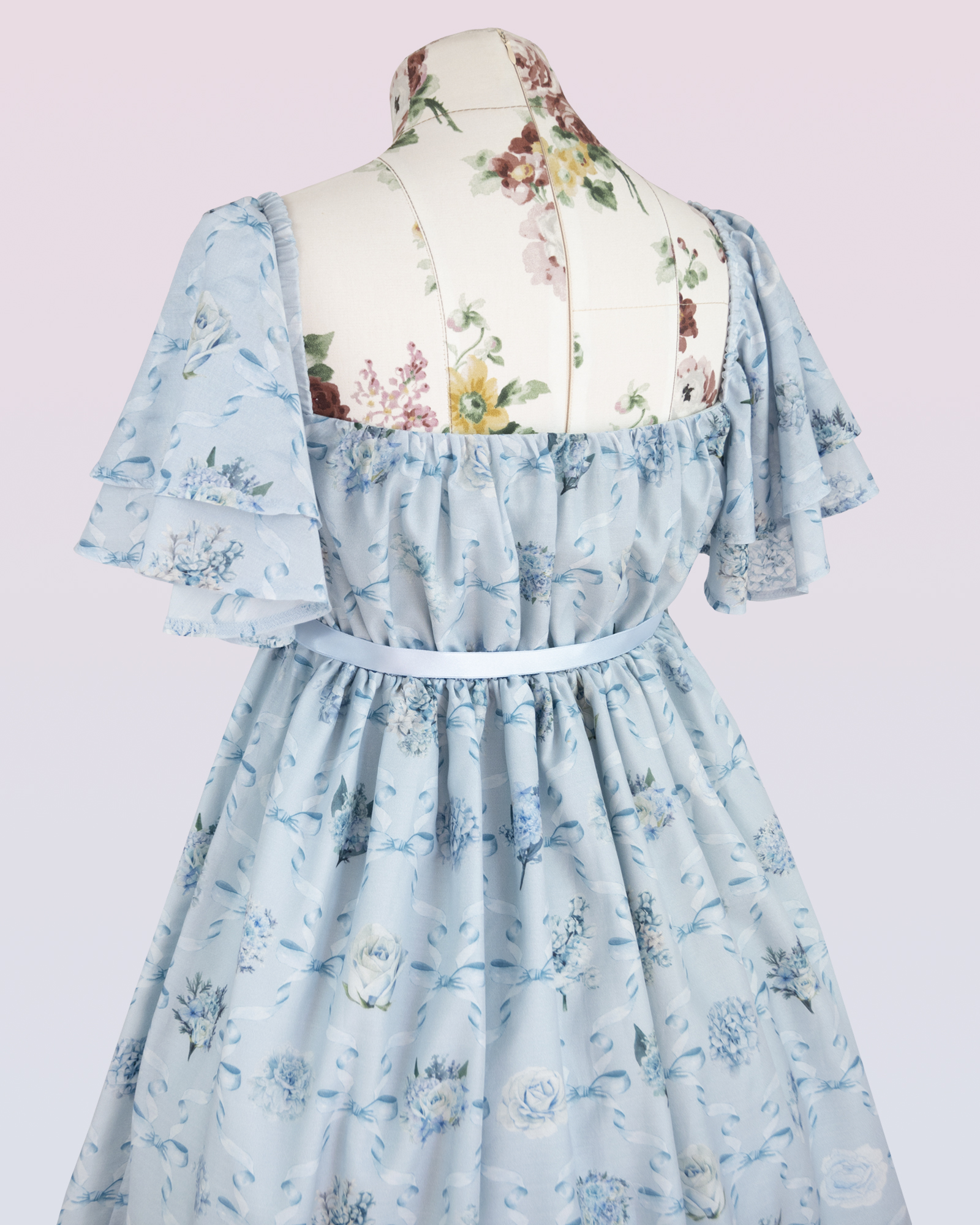 短い袖および花およびリボンの印刷物が付いている軽い青いシフォンの服